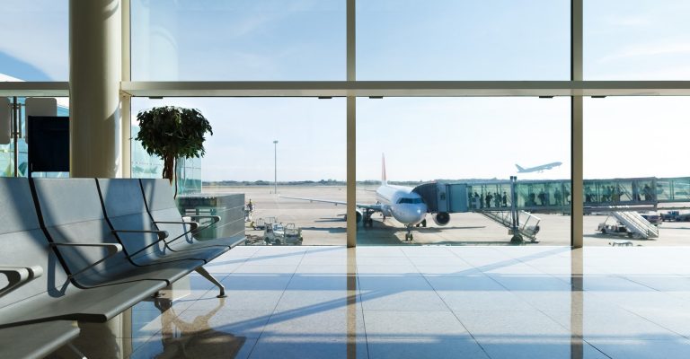 airport lobby with chairs looking out glass window with plane loading