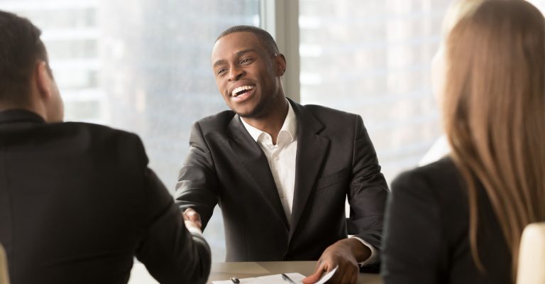 Man shaking hands with another man and woman at a meeting in an office