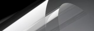 黒の背景で、白い光が当てられた透明な丸まったWillow® Glass