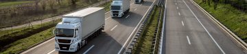 Several trucks in a row driving on street