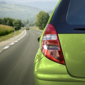 一辆行驶在路上的绿色汽车的左侧尾灯视图