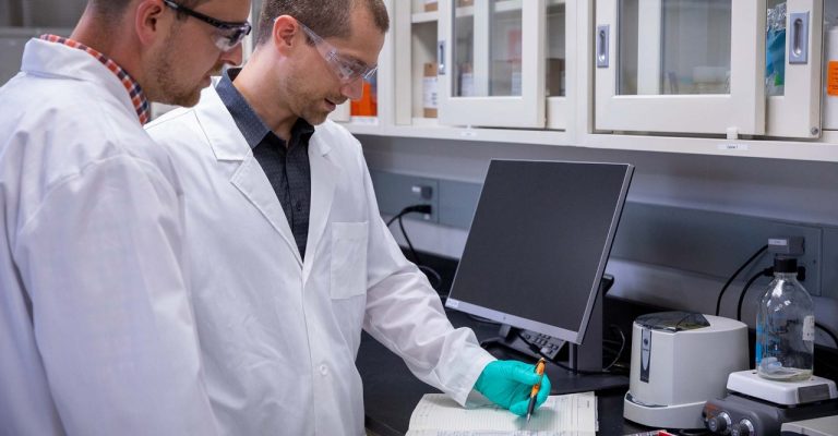 Two scientist writing notes in a notebook