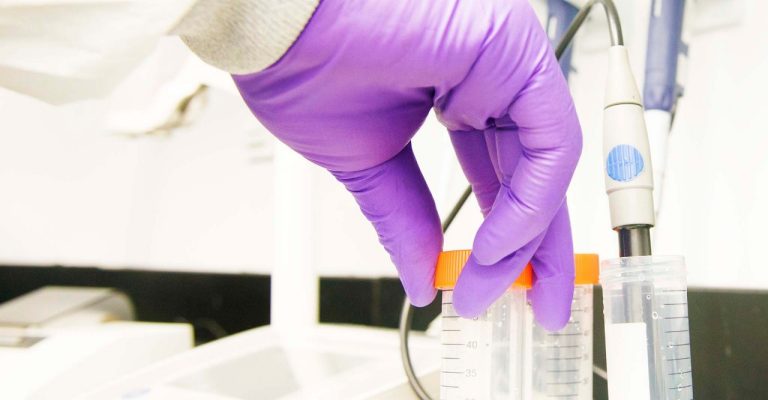 Scientist holding tube with gloved hand