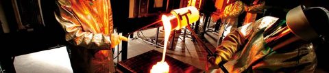  Workers in protective suits clamp, pour crucible of molten glass