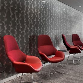 Red office chairs line wall covered in gray decorative glass