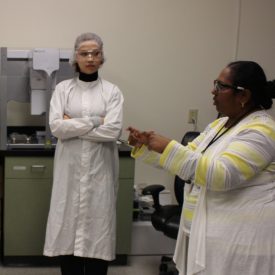 A Corning employee explains the plant's process to a student event attendee.