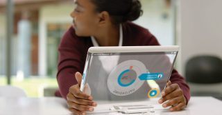 Girl holds transparent, glass electronic notebook in classroom setting