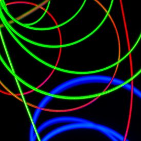 Loops of red, blue, green lighted fiber against black background