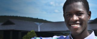 Closeup of Jonathan, a Corning intern, against building, hills backdrop