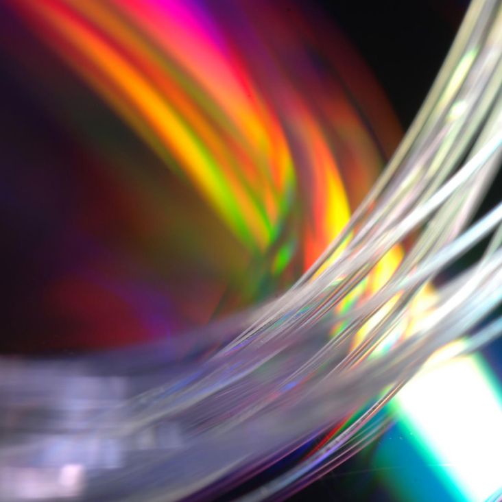 Bundle of clear glass fibers up close, multicolored backdrop