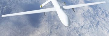 White drone flies over snowy, mountainous area