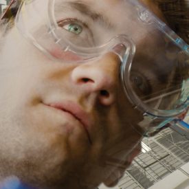 Montage: man in goggles looks upward, abstract image in background
