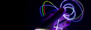 Hand holds bright, colorful loops of Fibrance in dark