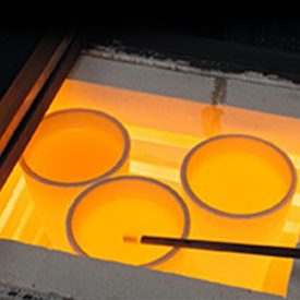 Round, cylinder-shaped glowy-hot glass is cooled