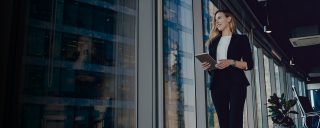 woman holding ipad and looking out the window at city building