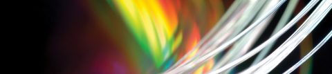 Bundle of clear glass fiber up close, multicolored-lighted backdrop