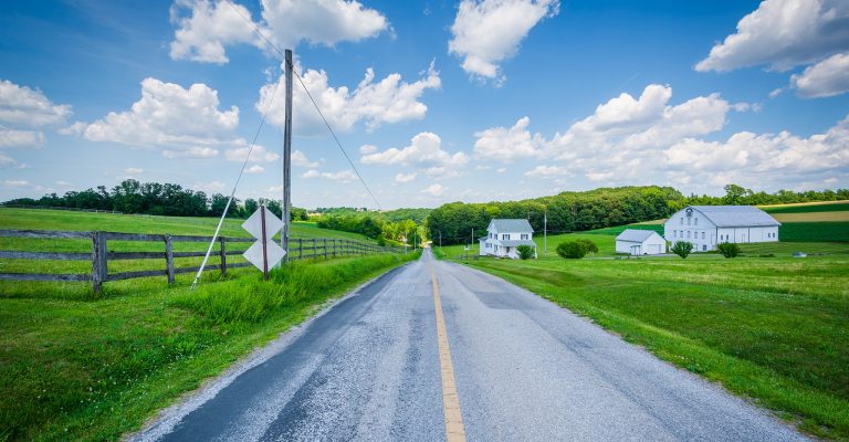 rural farm road with green grass and barn