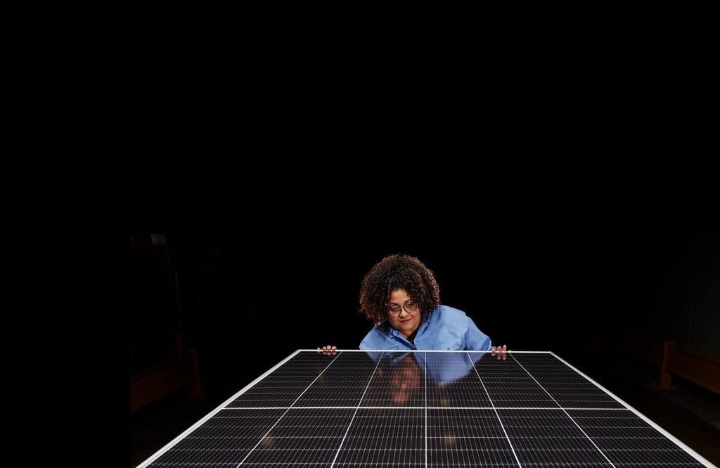 A Corning employee inspecting a solar panel against a dark studio backdrop