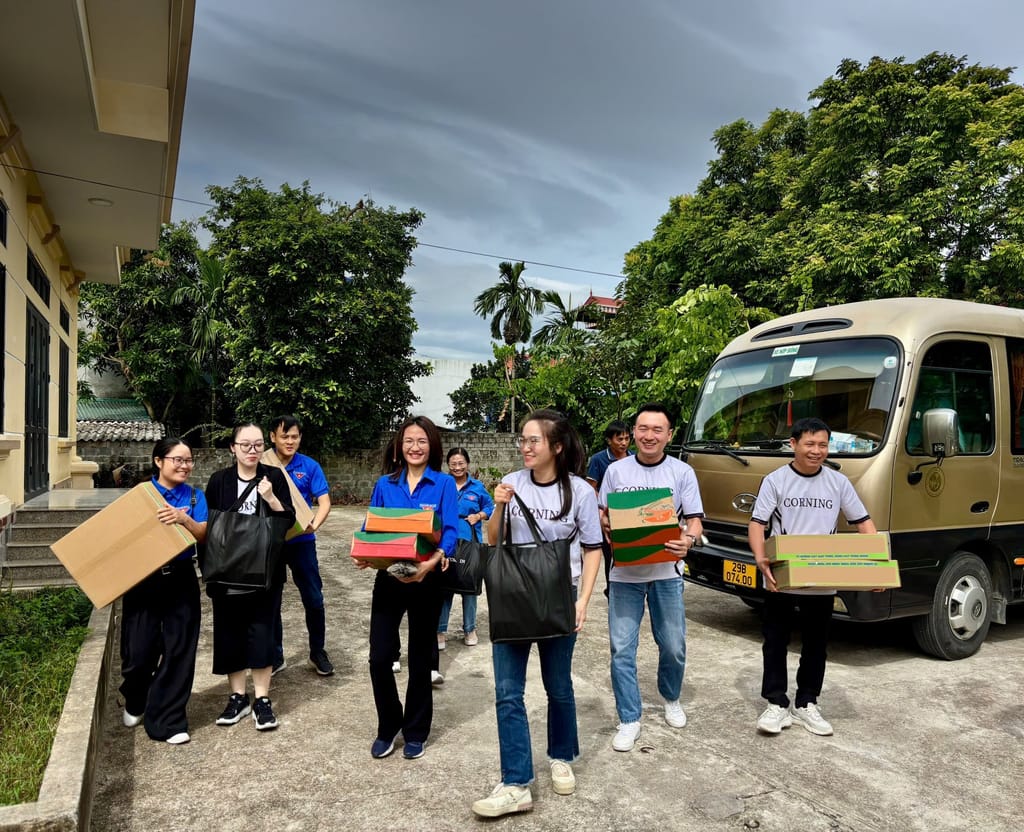Corning volunteers gathered outdoors with packages beside a Corning van