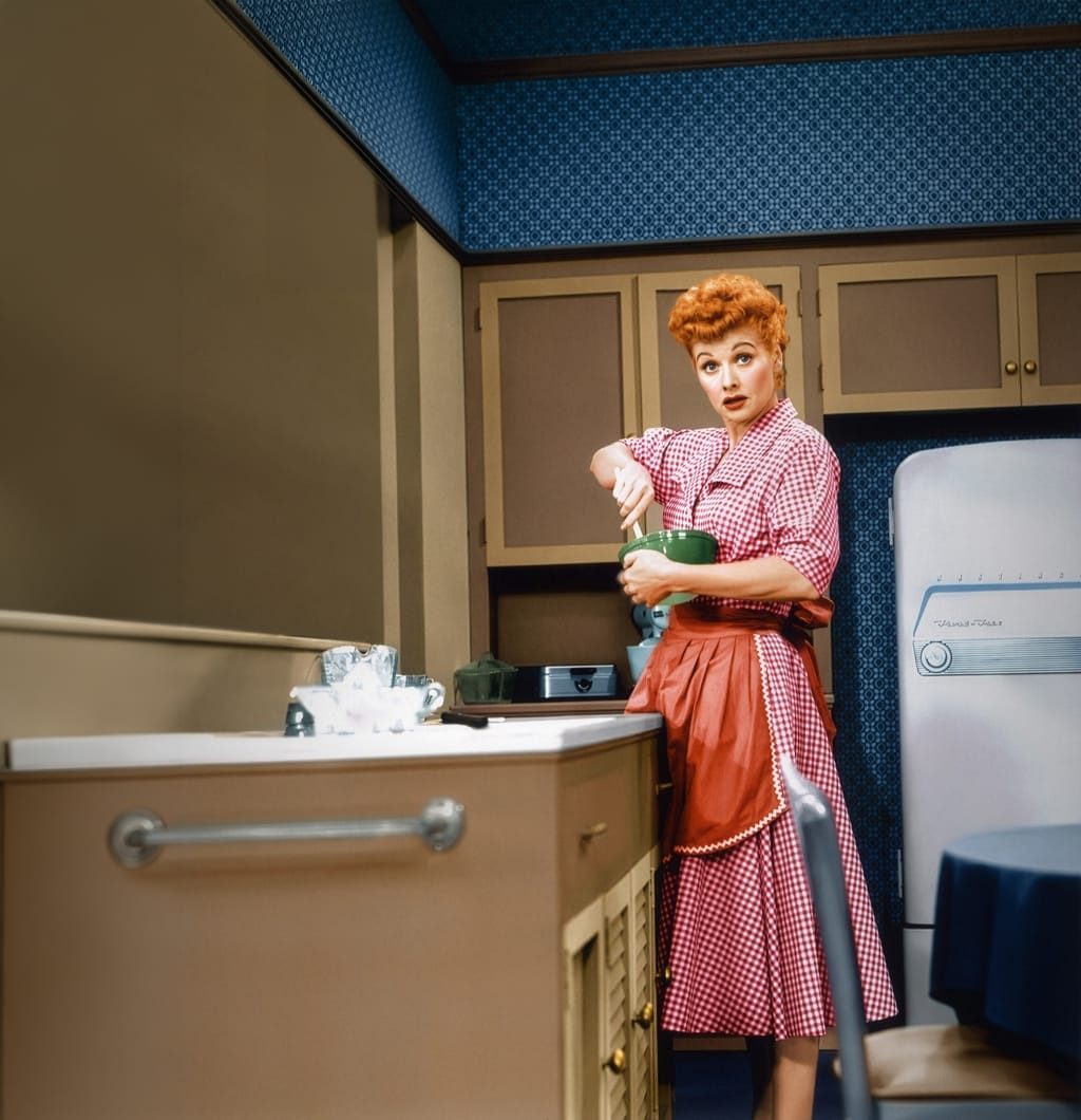 A woman holding a green Pyrex mixing bowl in a 1950s kitchen