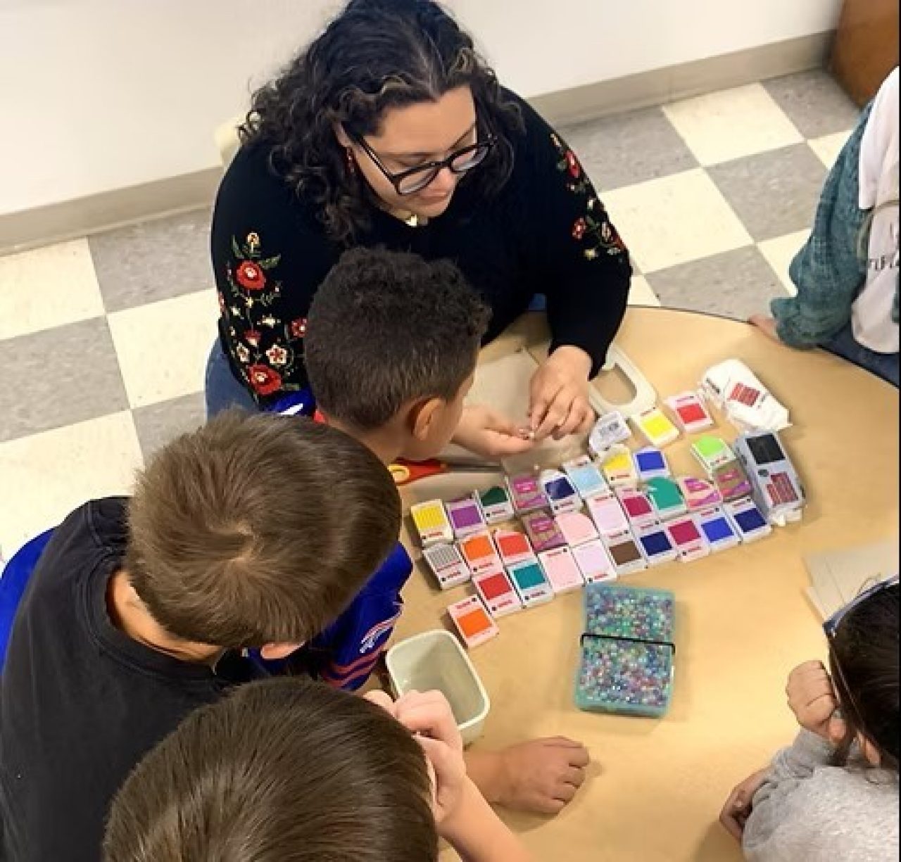 Woman with dark hair helps children use clay