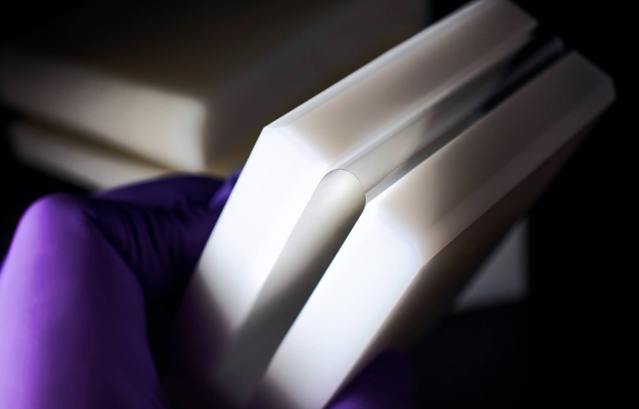 Disembodied hand in purple glove holding a contraption that keeps the glass in a bendable position