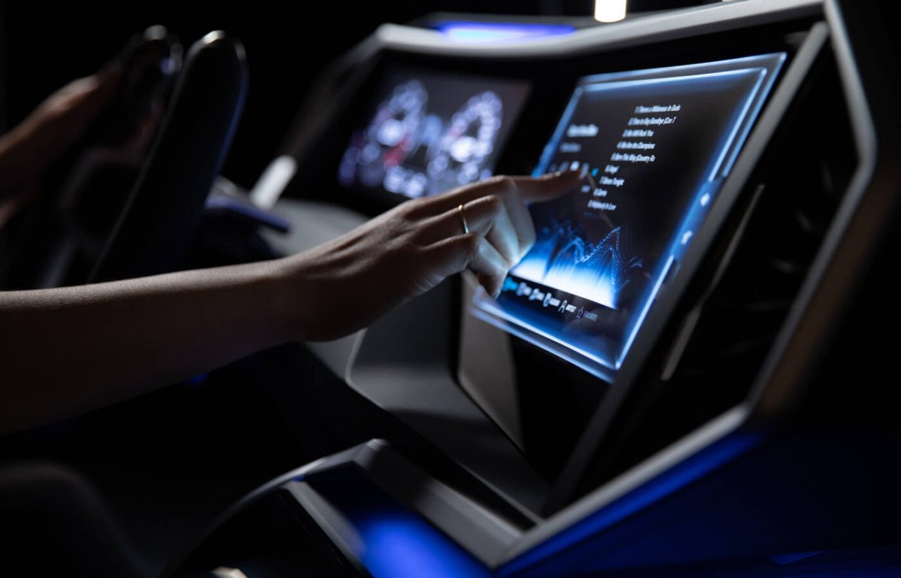A hand using the touchscreen of a digital center console in a car