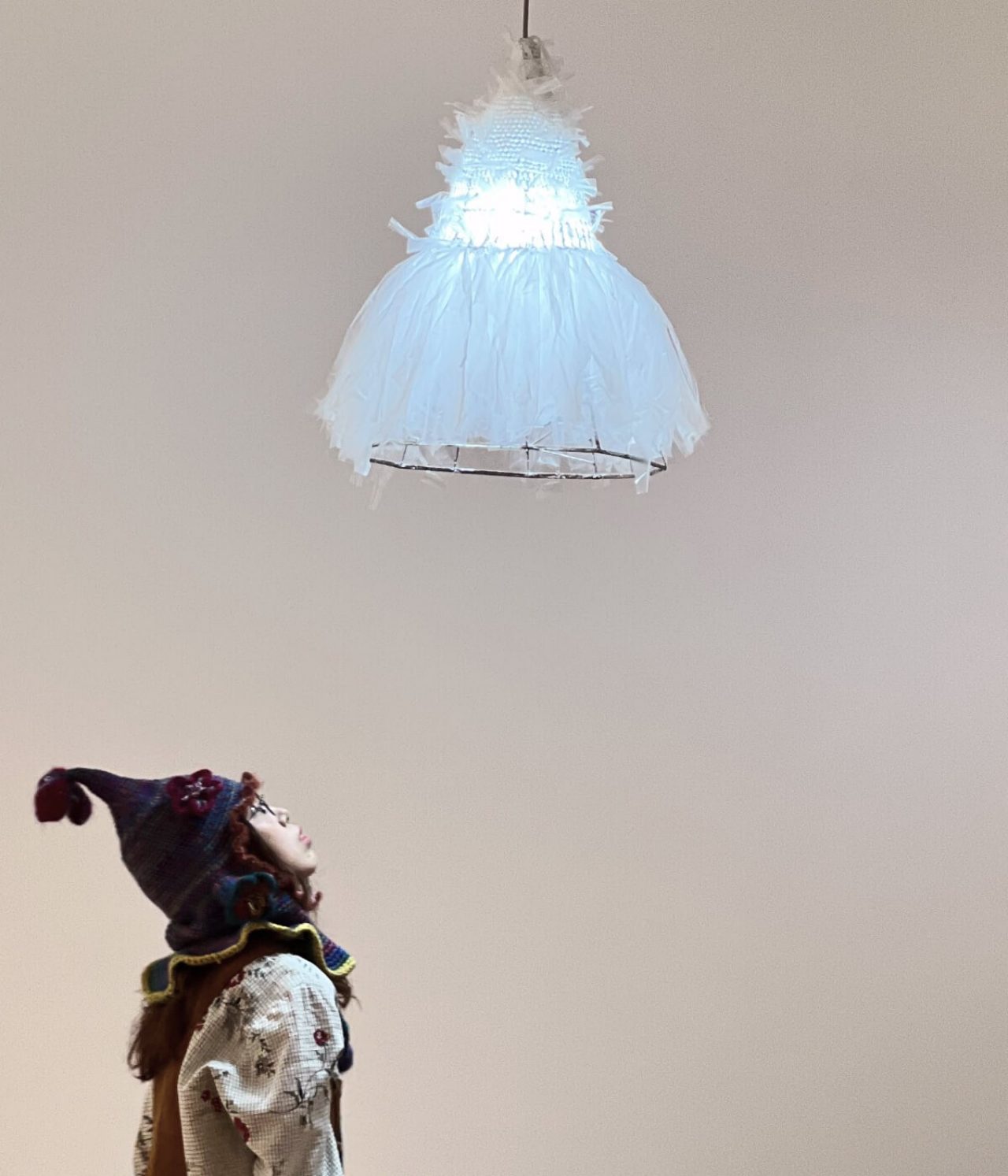 Chenyang gazes up to the art piece which takes on the form of a light shade. The shade is not dissimilar to the appearance of a white dress made of thin net-like material.