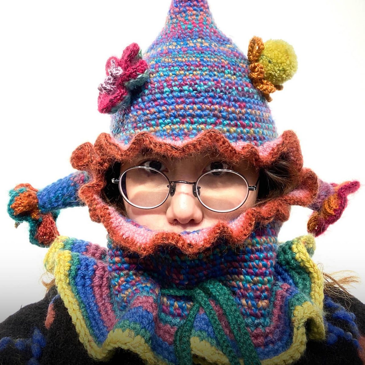 Chenyang Mu wears a colorful woollen hat and glasses while looking directly into the camera. Chenyang's mouth is covered by clothing.