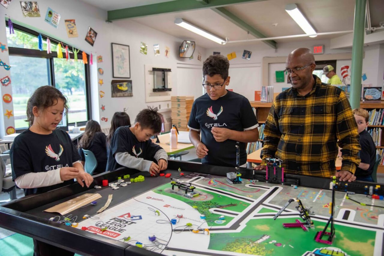 Eric Biribuze stands by a worktable with STELA students