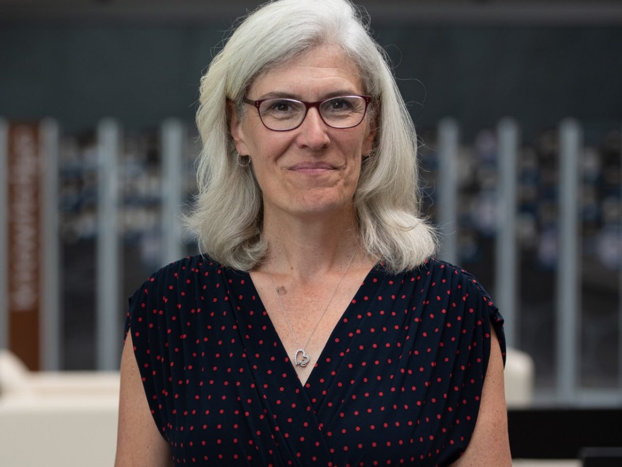 Shawn Markham looking directly at the camera in a navy blue dress with the lab in the background.